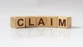 Claim word on wooden cube on gray background