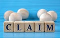 CLAIM - word on wooden cubes on a blue background with wooden round balls Royalty Free Stock Photo