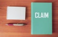 Claim, the word is written on a green notepad and a wooden table, next to a blank notepad for writing Royalty Free Stock Photo