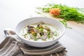 clam chowder in a white bowl with chopped chives