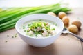 clam chowder in a white bowl with chopped chives