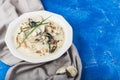 Clam chowder in a white plate. The main ingredients are shellfish, broth, butter, potatoes and onions