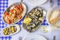 Clams served on silverware, tomato salad, bread, olives and whit