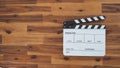 Clapper board or movie slate use in video production, film and cinema industry. It`s white color on wood background with flare Royalty Free Stock Photo