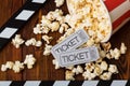 Clapper, spilled popcorn and movie tickets on a background of boards Royalty Free Stock Photo