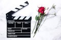 Clapperboard and fresh roses on marble table. Love is just acting concept.