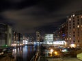 Clarence dock leeds at night with moored barges and moonlit clouds over brightly illuminated waterside buildings reflected in the Royalty Free Stock Photo