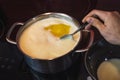 Clarification of butter, clarified butter in a steel pot mixed with steel spoon. Removing foam from butter