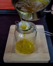 Clarification of butter. Pouring clarified butter into a jar through a gauze and a metal strainer on a wooden chopping board