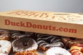 A cardboard box of a dozen donuts bought from the chain store Duck Donuts