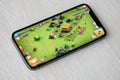 Clash of Clans mobile iOS game on iPhone 15 smartphone screen on wooden table during mobile gameplay