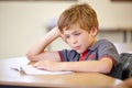 Class, book and bored child at desk, learning and education with school exam. Reading notebook, studying for test and Royalty Free Stock Photo