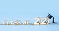 Class of 2023 concept. Wooden number 2023 with graduated cap on colored background