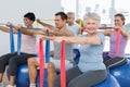 Class holding out exercise belts while sitting on fitness balls Royalty Free Stock Photo