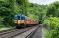 A Class 455 South Western Railway passenger service train approaches a tunnel in the Surrey countryside at Norbury Park