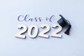 Class of 2022 wearing graduate cap on wooden number 2022 on grey background with glitter