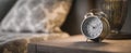 The classic alarm clock on a bedside table in a cozy bedroom setting..AI generated image Royalty Free Stock Photo
