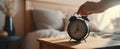 The classic alarm clock on a bedside table in a cozy bedroom setting..AI generated image Royalty Free Stock Photo