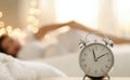 Classic alarm clock on bedside table with cozy lights and soft focus background at night Royalty Free Stock Photo