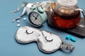 Classic alarm clock, sleeping mask, tea pot on blue pastel background. Minimal concept of rest, quality of sleep, good Royalty Free Stock Photo