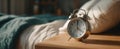 The classic alarm clock on a wooden bedside table in a serene bedroom setting..AI generated image Royalty Free Stock Photo