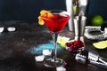 Classic alcoholic cocktail cosmopolitan with vodka, liqueur, cranberry juice, lime, ice and orange zest, dark bar counter Royalty Free Stock Photo