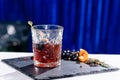 Classic alcoholic Godfather cocktail in rocks glass on blue back