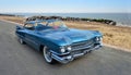 Classic American Blue Cadillac Motor Car parked on seafront promenade beach and sea in background. Royalty Free Stock Photo