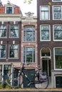 classic Amsterdam houses in row with narrow small house in middle and bicycle in foreground