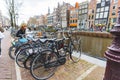 Classic Amsterdam view - many bikes standing next to each other by the canal. Outdoor shot. Cloudy weather.