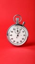 Classic analog stopwatch with white face and black markings on a solid red background Royalty Free Stock Photo