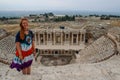 A classic antique Greek theater in Pamukkale, Denizli, Turkey and a white young woman in a hippie dress Royalty Free Stock Photo