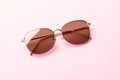 Classic aviator mirrored flat lens sunglasses with golden metal frame closeup on pink background