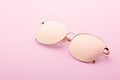 Classic aviator mirrored flat lens sunglasses with golden metal frame closeup on pink background