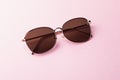 Classic aviator mirrored flat lens sunglasses with golden metal frame closeup on pink background