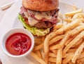 A classic bacon and cheeseburger with french fries and ketchup sauce closeup Royalty Free Stock Photo