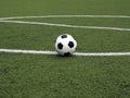 White and black ball for playing soccer lays on green synthetic grass near center of sport playground Royalty Free Stock Photo