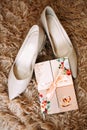 Classic beige bridal shoes on a shaggy rug. Nearby lies an invitation greeting card. Royalty Free Stock Photo