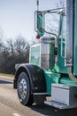 Classic big rig green semi truck tractor driving on the wide road