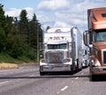 Classic big rig and modern semi truck with trailers going side b Royalty Free Stock Photo