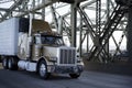 Classic big rig semi truck with refrigeration unit on reefer semi trailer running on the Interstate bridge Royalty Free Stock Photo