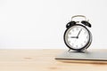 Classic black alarm clock and laptop on wooden table with white background and copy space Royalty Free Stock Photo