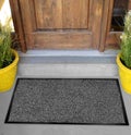 Classic black grey welcome door mat with black border outside home with yellow flowers and leaves Royalty Free Stock Photo