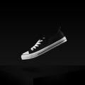 Classic black and white sneaker levitating in air stylish and fashion shot . Shoes on dark background Royalty Free Stock Photo