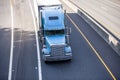 Classic blue big rig bonnet semi truck transporting cargo in refrigerator semi trailer moving on wide road Royalty Free Stock Photo