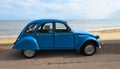 Classic Blue Citroen 2CV deux chevaux parked on seafront promenade.