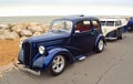 Classic Blue Ford Motor Car with trailer shaped like a VW Camper Van parked on seafront promenade.