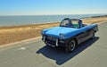 Classic Blue Triumph Herald Convertible Car being driven along Seafront Promenade. Royalty Free Stock Photo
