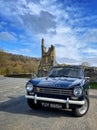 Triumph Herald 13/60 convertible parked by a ruined abbey