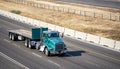 Classic bonnet day cab green semi truck with empty flat bed semi trailer with front protection wall running on the highway road to
